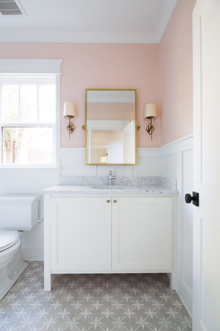 Powder Room Design by Laura Design Co., Paint is Farrow & Ball Pink Ground, Floor Tile is by Laura Ashley for The Tile Shop, Carrara Marble Countertop, Chantilly Lace Vanity Paint by Benjamin Moore. Sconces are Visual Comfort & Mirror is Pottery Barn